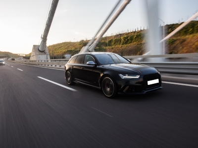 Ein schwarzes Auto fährt auf einer Autobahn.